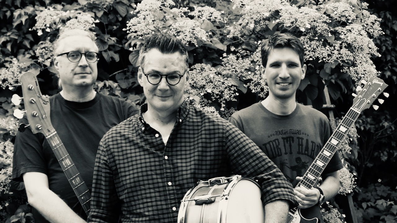 Drei Musiker mit Bass, Trommel und Gitarre
